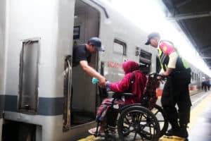 Petugas kereta api mendampingi seorang lansia saat memasuki kereta api. Foto: Dep/Karisma.